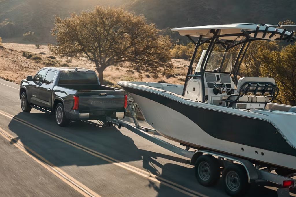 2025 Toyota Tundra towing a large trailer on a scenic highway, showcasing its 12,000-pound towing capacity.