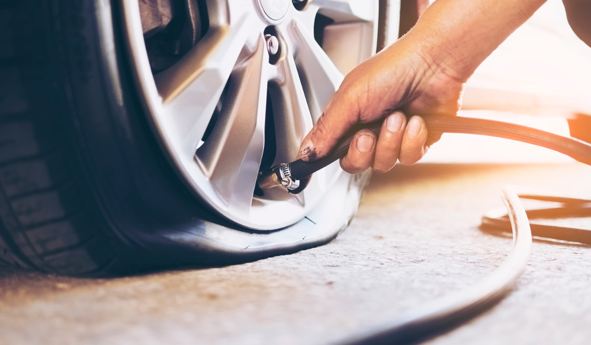 Toyota Vallejo Service Center employee inflating a flat tire on a Toyota vehicle using an air hose attached to the wheel valve.